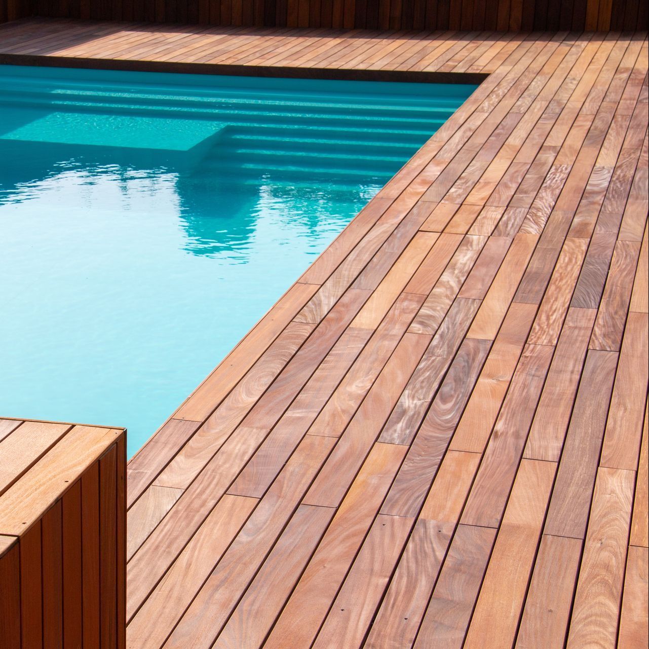 a wooden deck with a swimming pool in the background