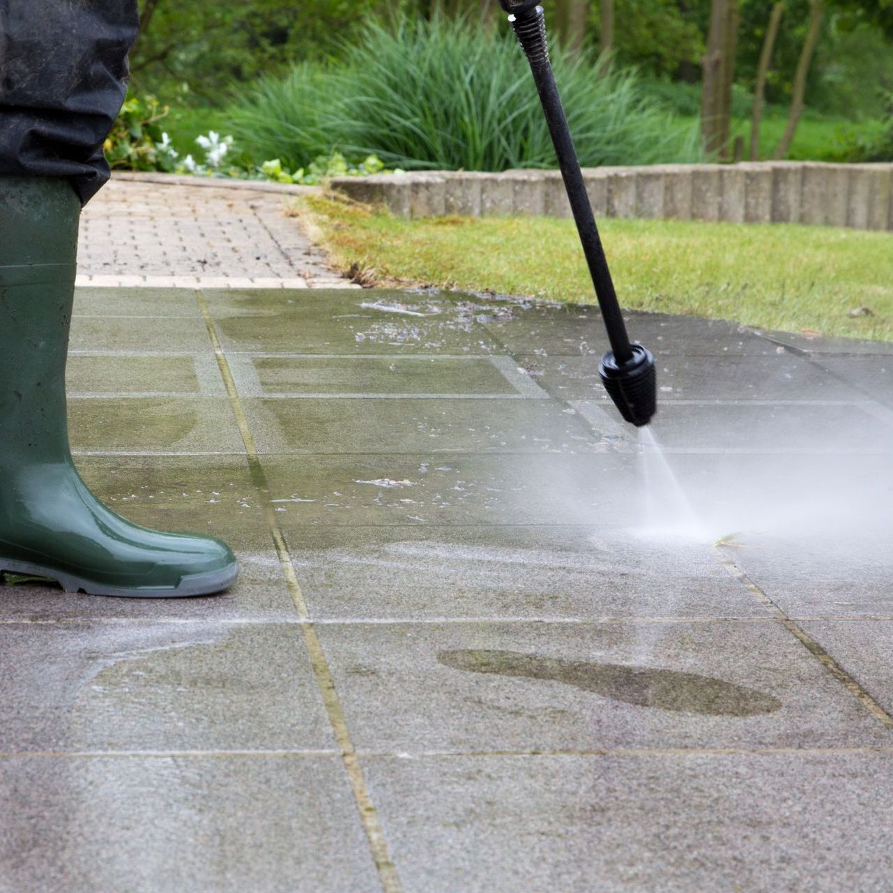 a person is using a high pressure washer to clean a concrete path