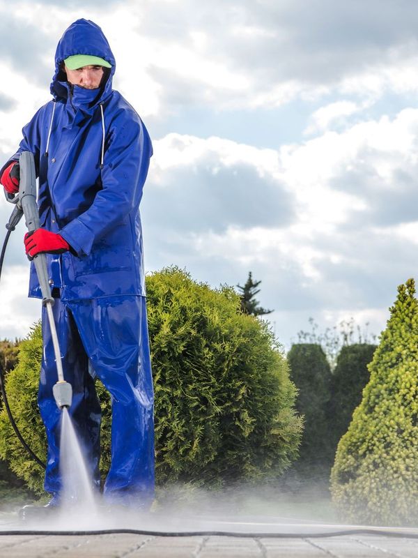 a man in a blue jacket is using a high pressure washer