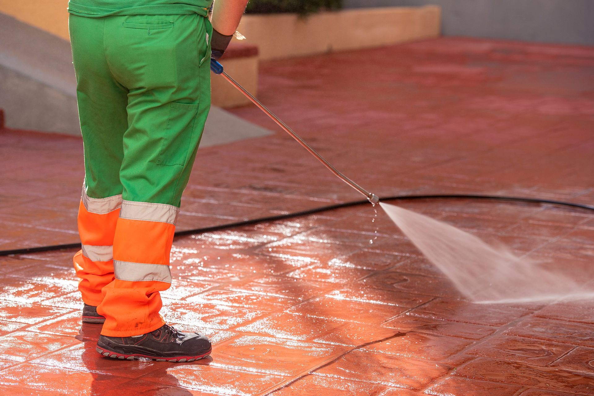 a man in green and orange pants is using a high pressure hose