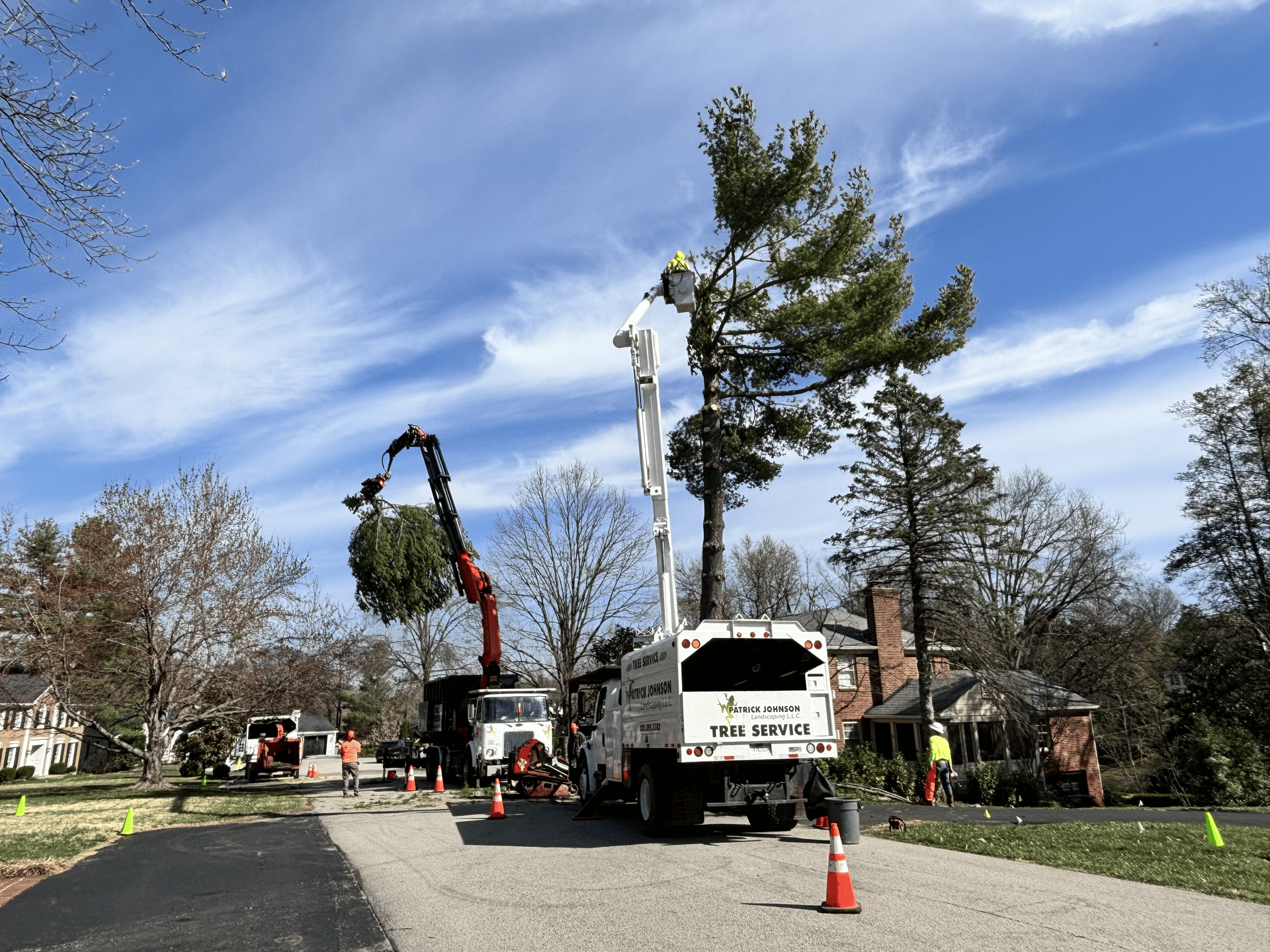 Lumberjack in safety gear using an orange chainsaw to cut a large log; wood chips fly.
