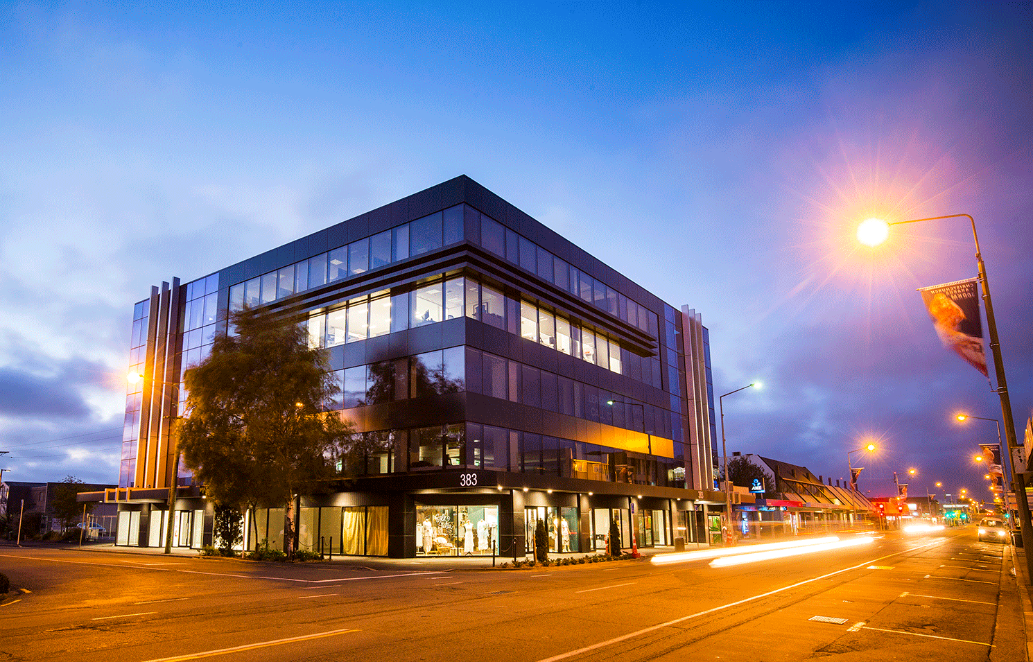 A large building is sitting on the corner of a city street at night.