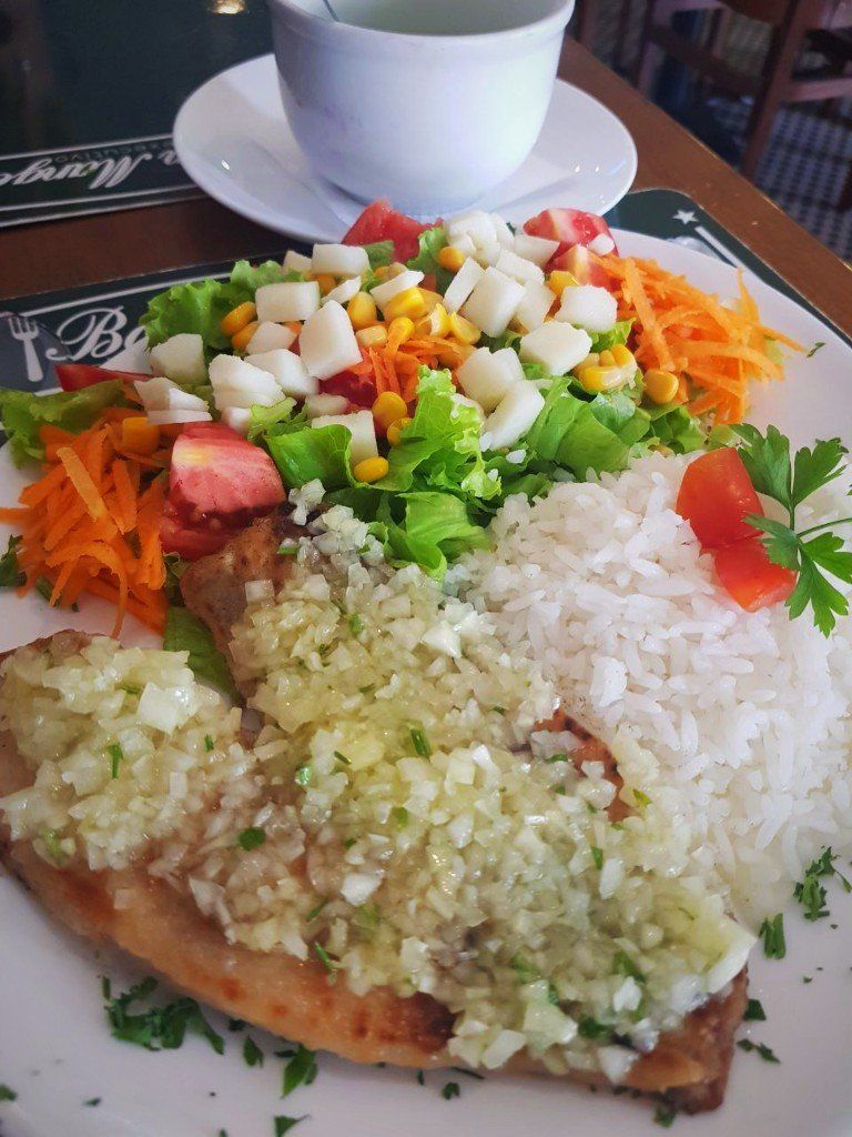 Um prato de comida com arroz, legumes e uma xícara de chá sobre uma mesa.
