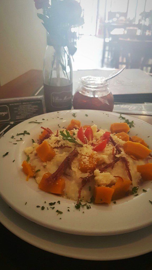 Um prato de comida está sobre uma mesa ao lado de um vaso de flores.