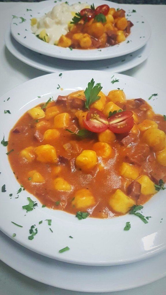 Dois pratos de comida com nhoque e tomate sobre uma mesa.