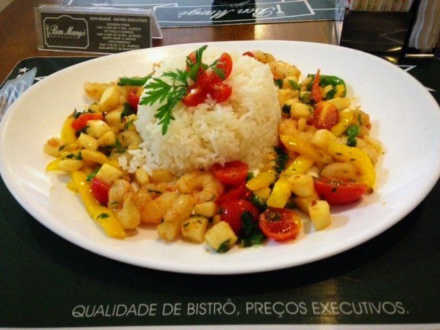 Um prato branco coberto com arroz de camarão e legumes