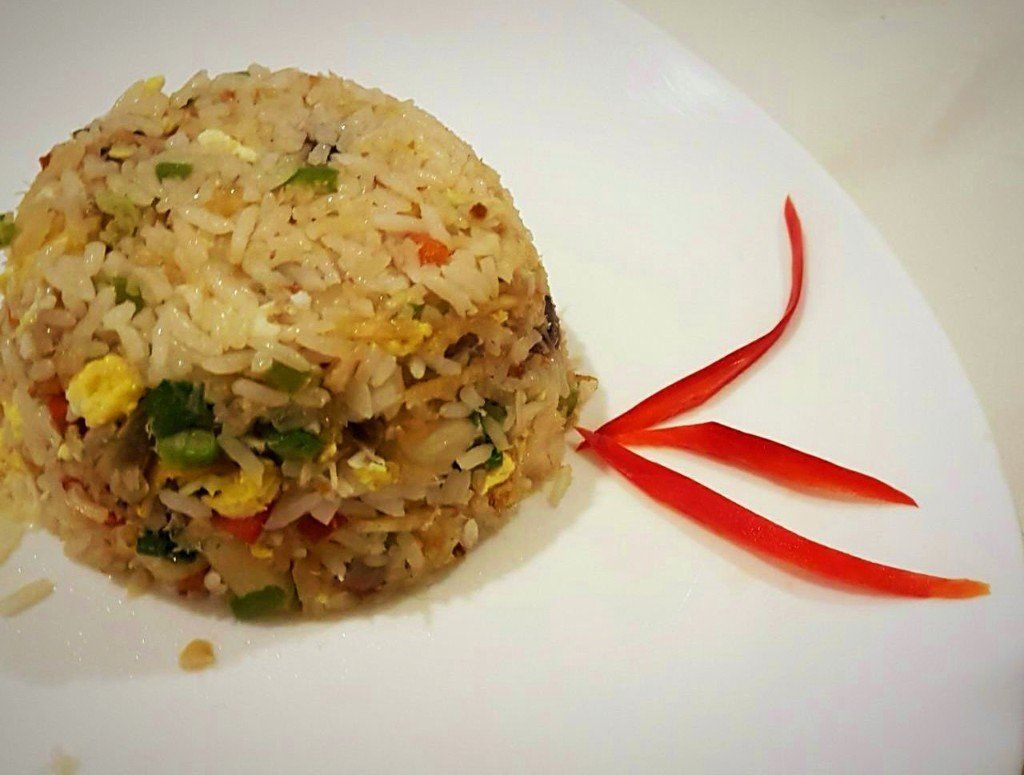 Um prato branco coberto com arroz e legumes com uma fita vermelha