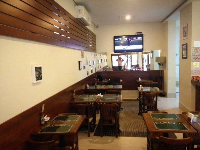 Um restaurante com mesas e cadeiras e uma TV na parede