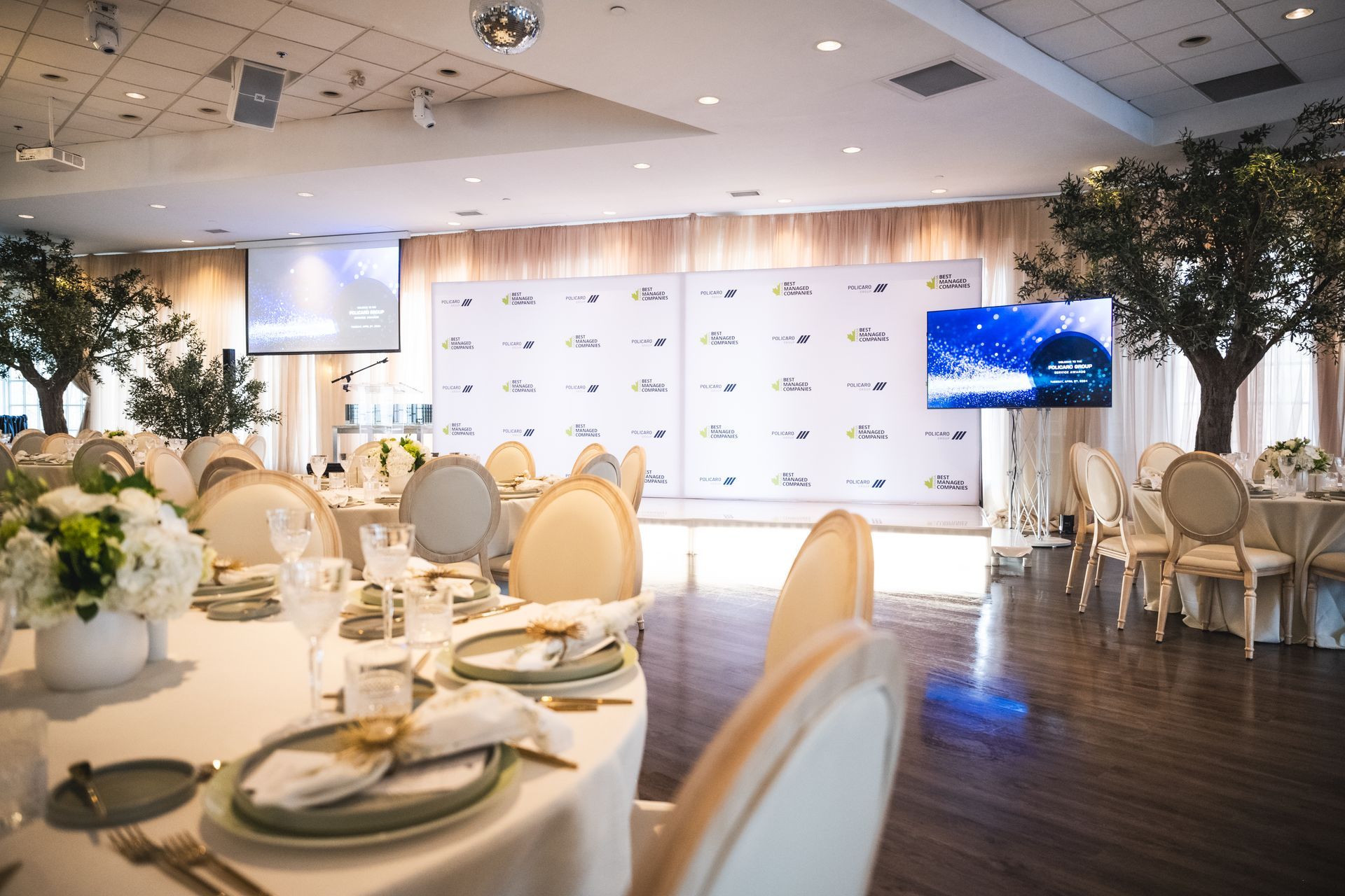 A large room with tables and chairs set up for a wedding reception.