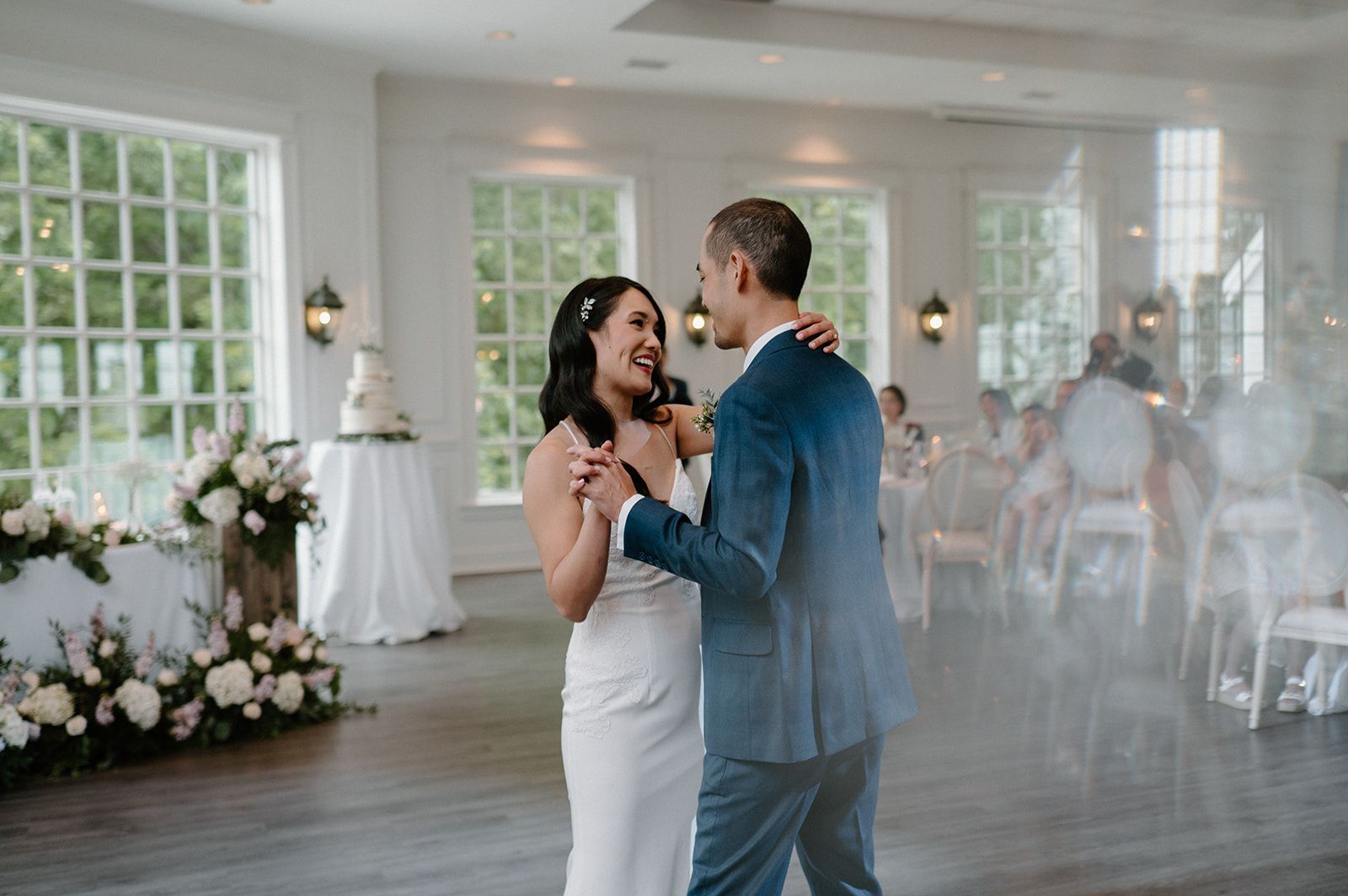 A bride and groom are dancing in a room at their wedding reception.