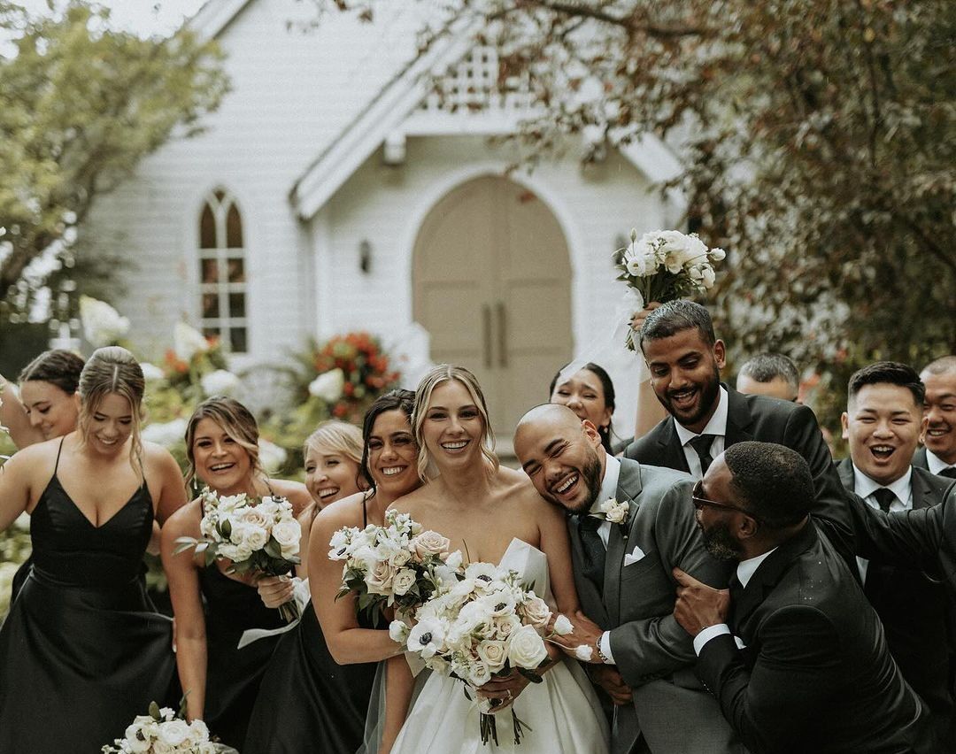 A bride and groom are posing for a picture with their wedding party.