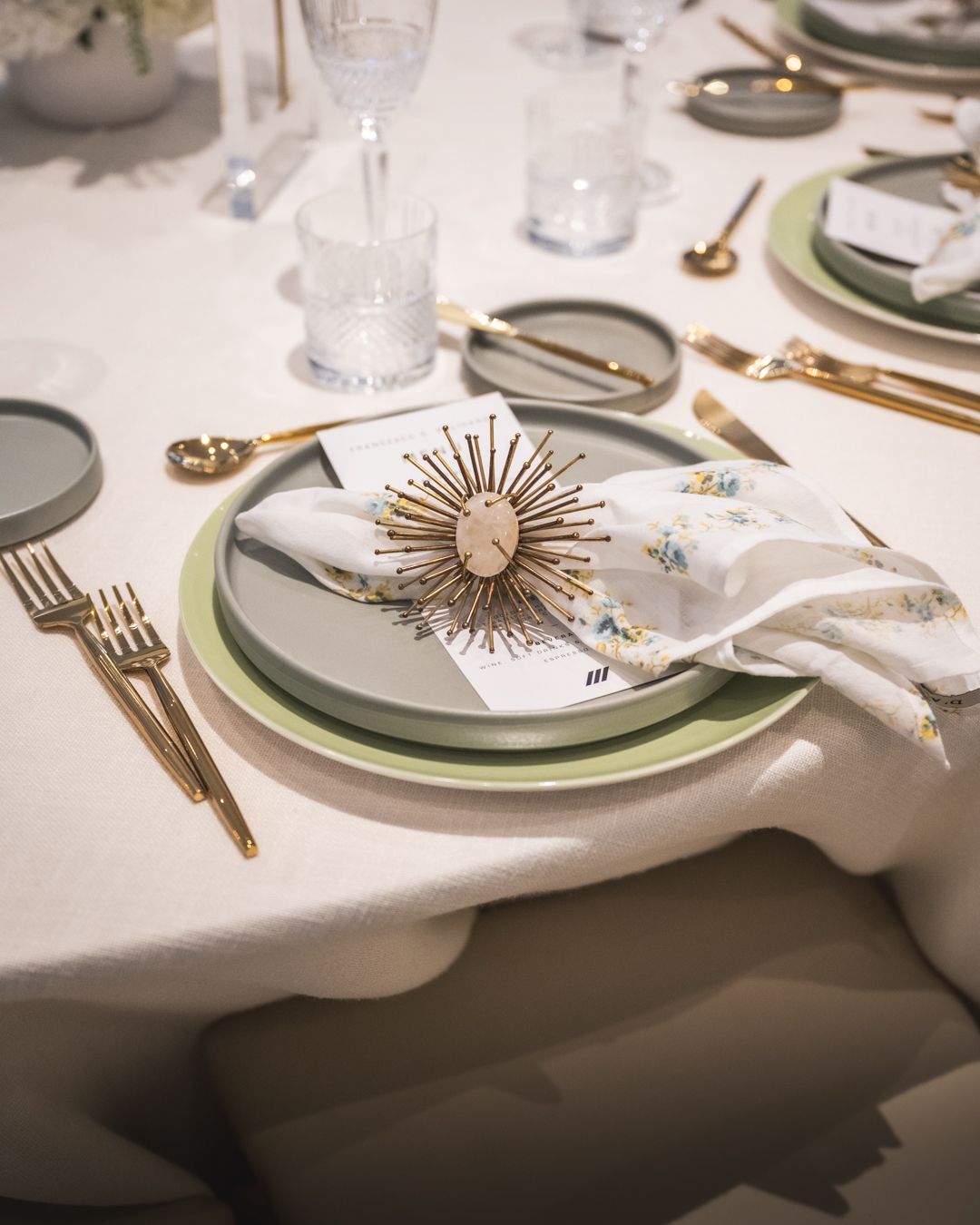 A table setting with plates , forks , spoons and napkin rings