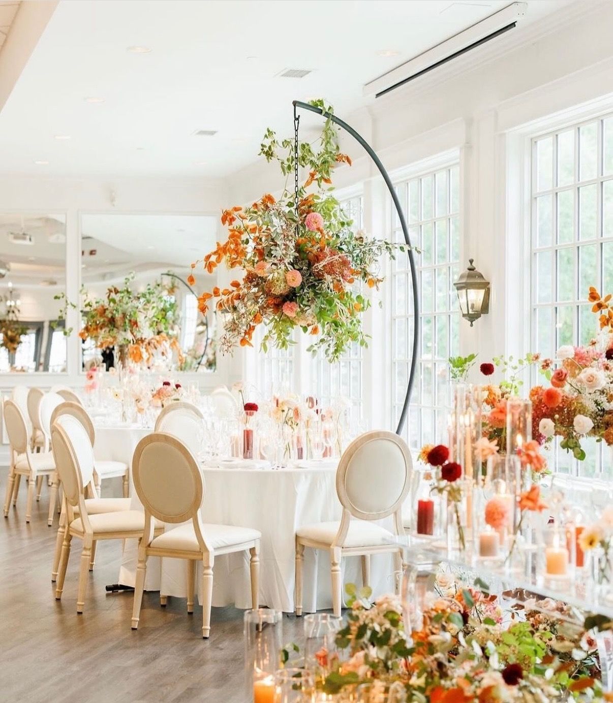 A large room with tables and chairs decorated with flowers and candles.