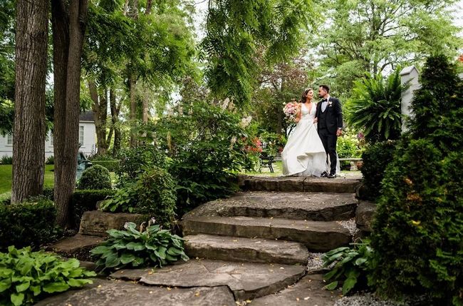 A bride and groom are standing on a set of stone stairs in a garden.