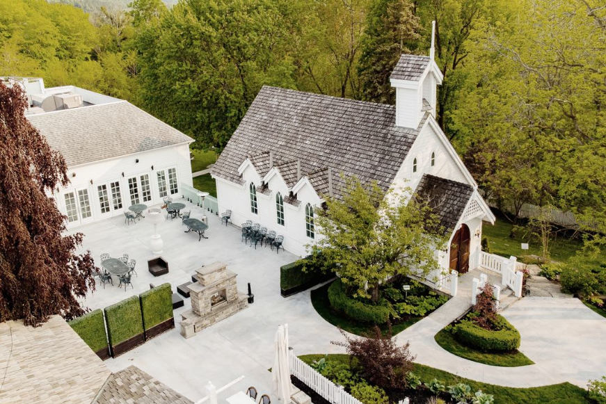 An aerial view of a small white church surrounded by trees.