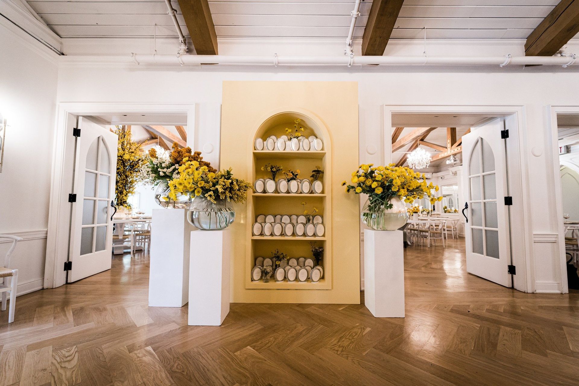 A room with a yellow wall and a shelf filled with vases of flowers.