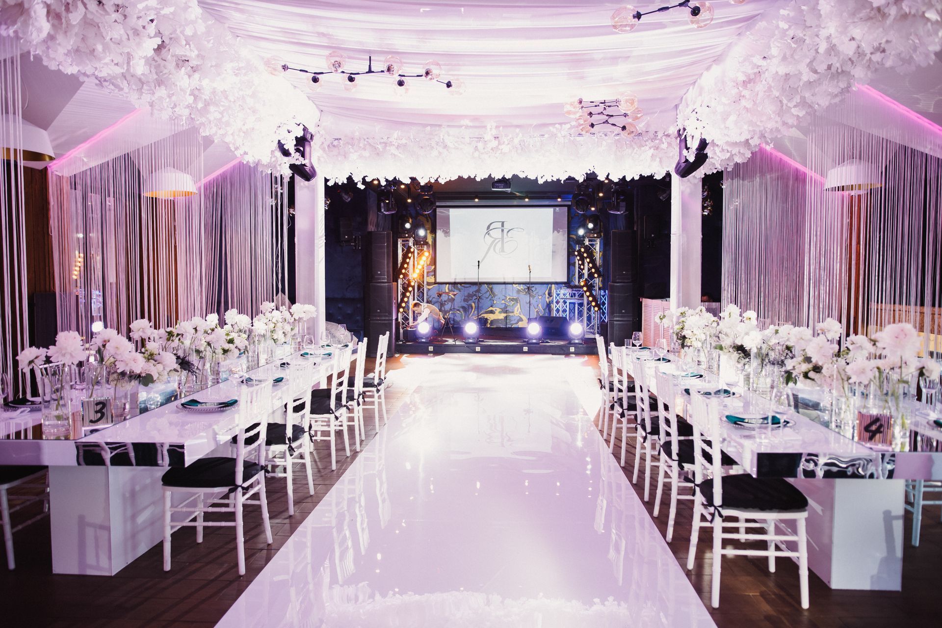 A large room with tables and chairs set up for a wedding reception.