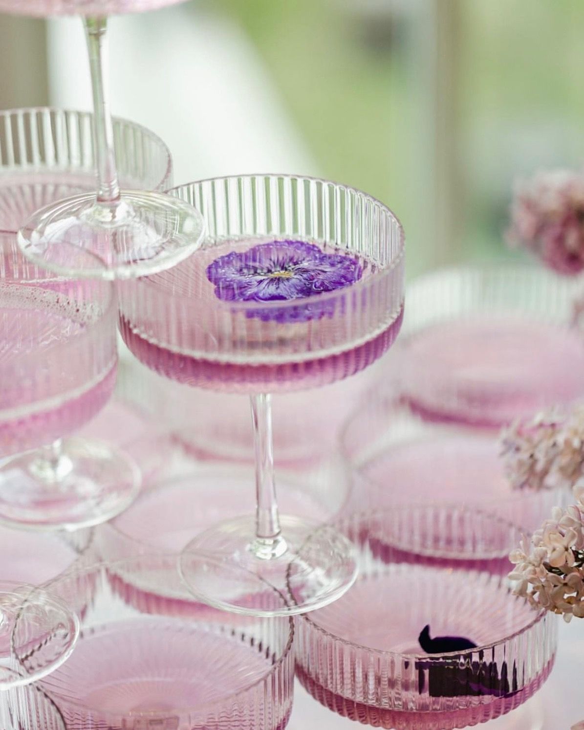 A stack of pink champagne glasses with a purple flower in the middle.