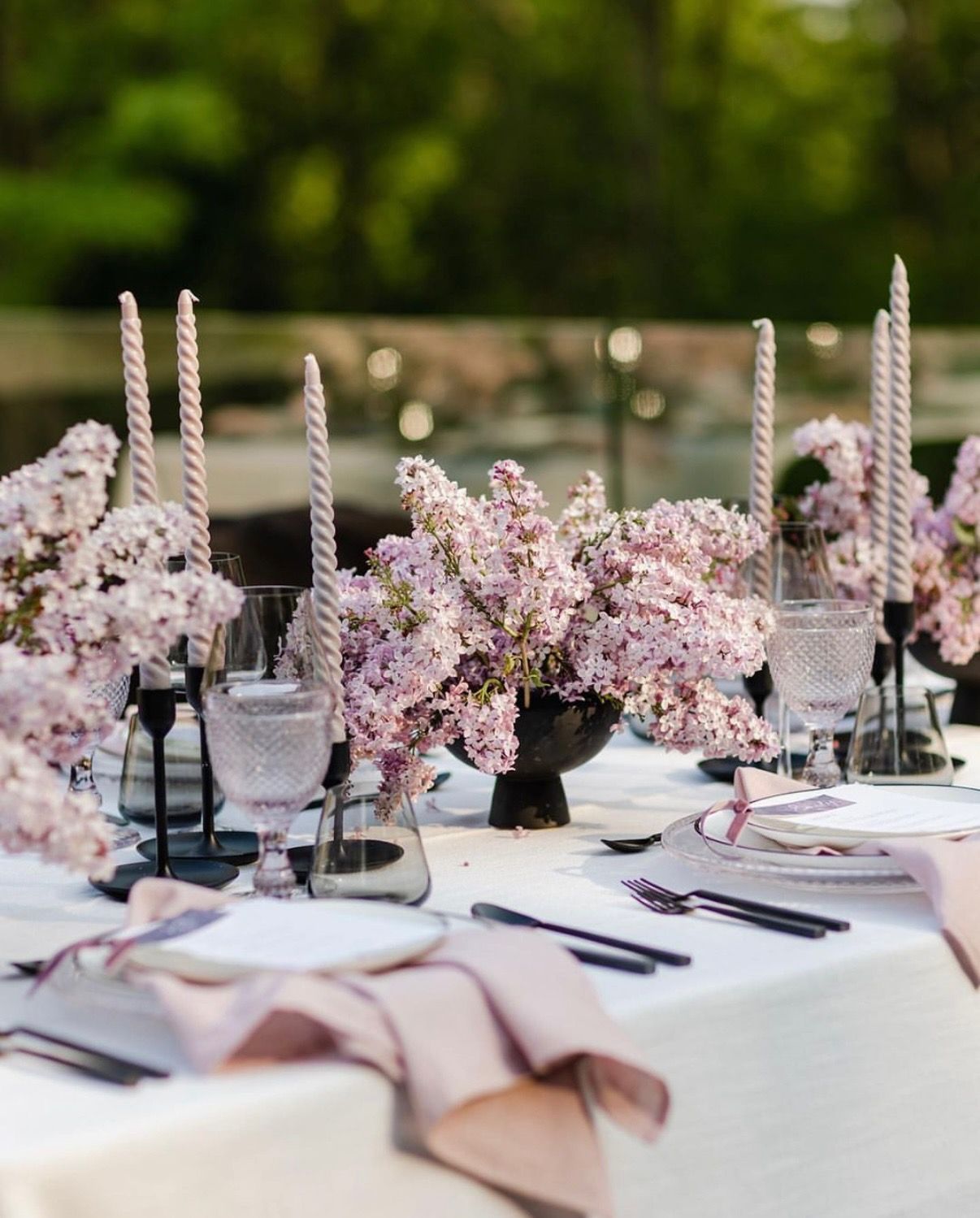 A table set for a wedding reception with pink flowers and candles.