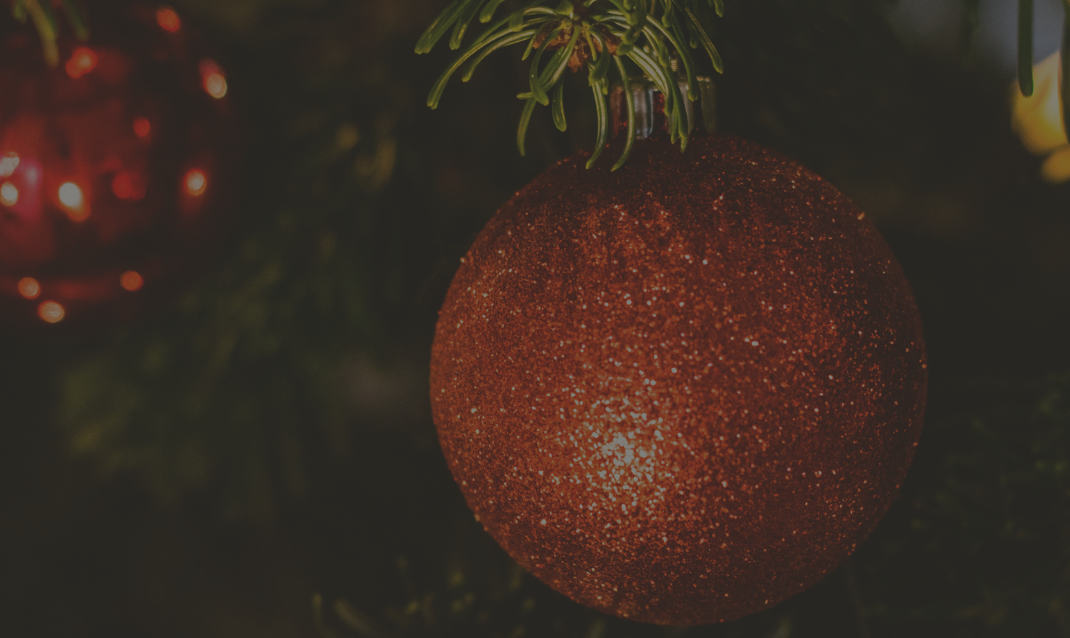 A close up of a christmas tree with a red ball hanging from it.