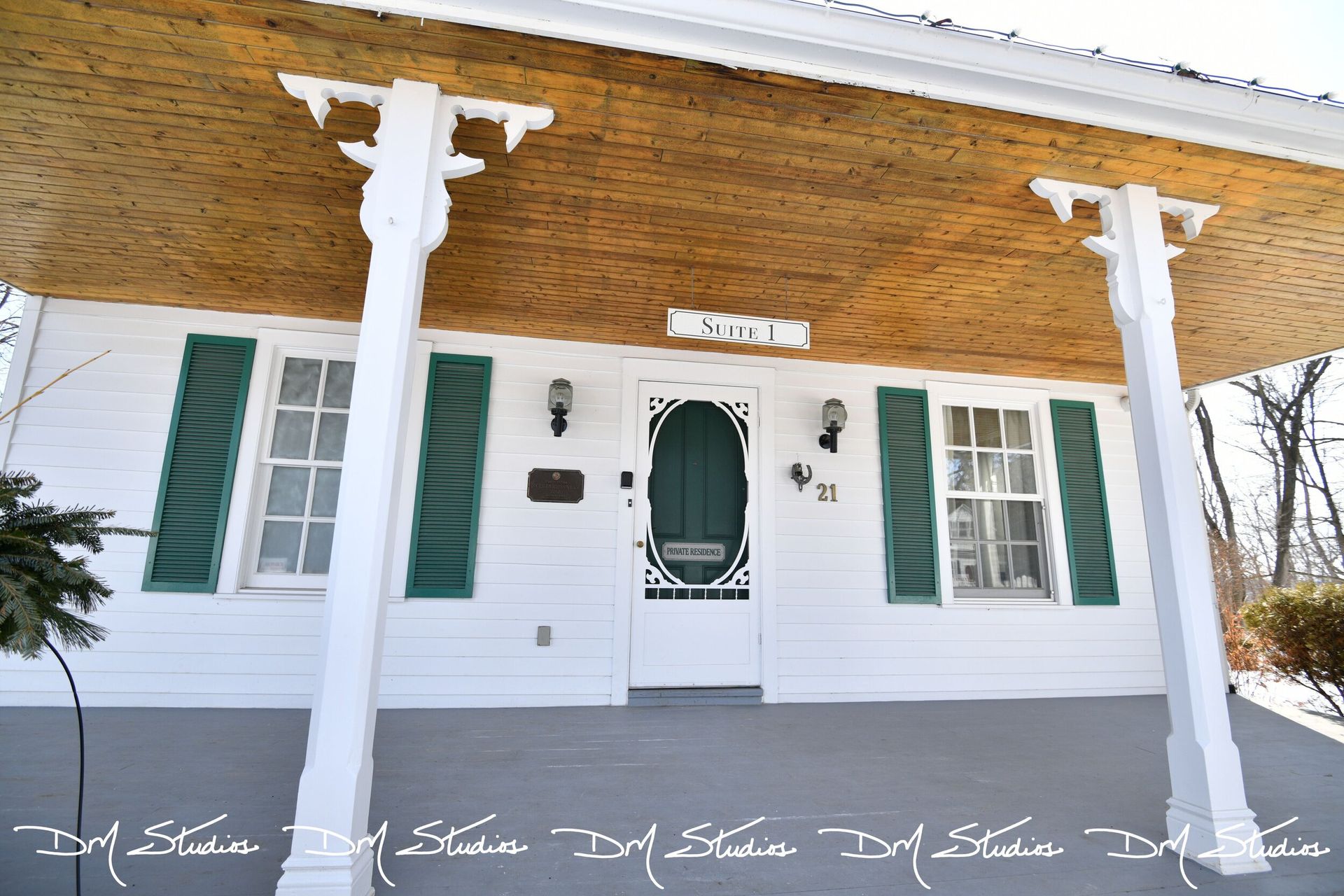 The front of a white house with green shutters