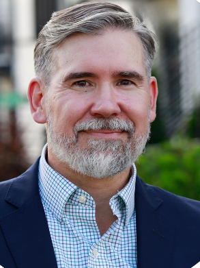 A man with a beard and a blue jacket is smiling for the camera.