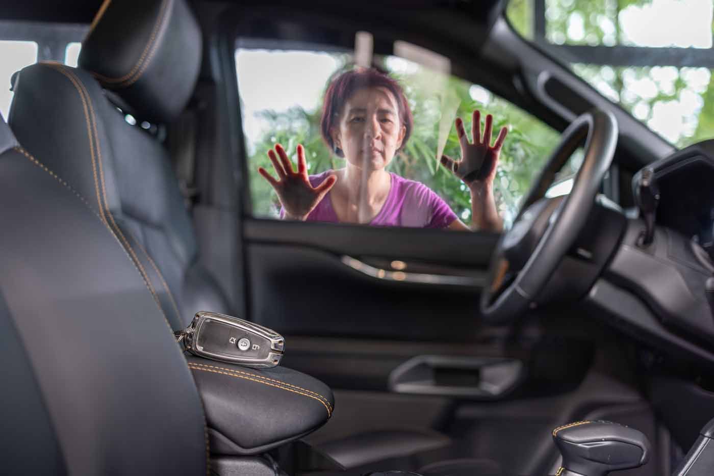 A woman is looking through the window of a car.