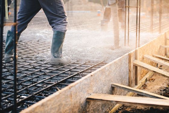 A man is pouring concrete on a construction site.