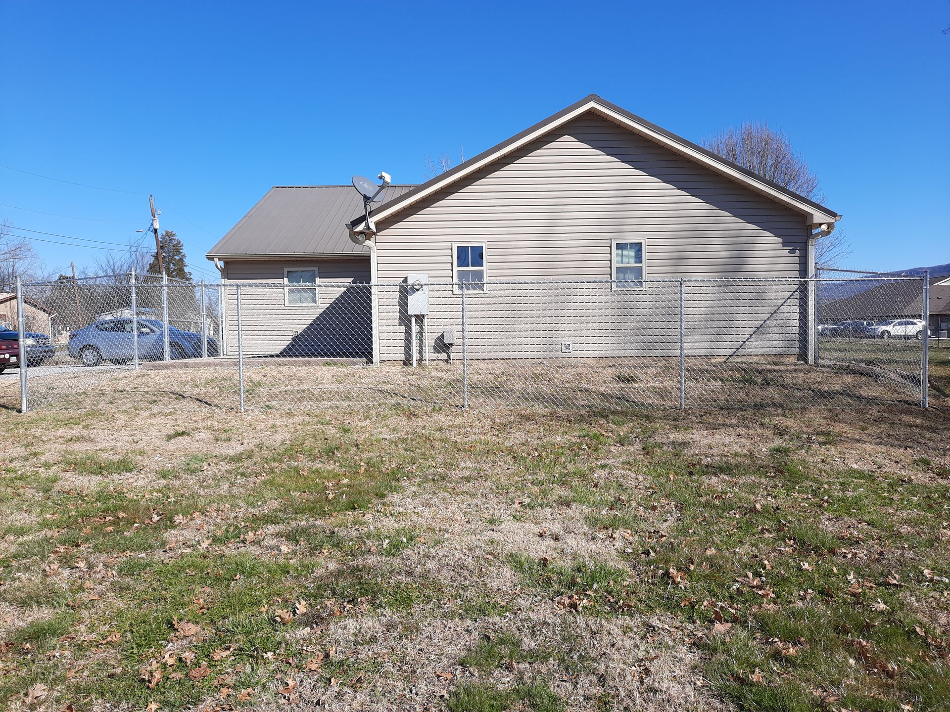 The back of a house with a chain link fence around it.