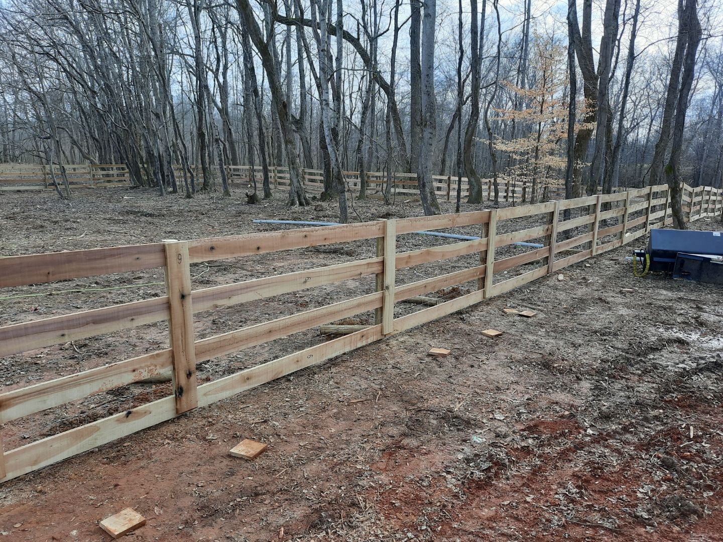 A wooden fence is being built in the middle of a forest.