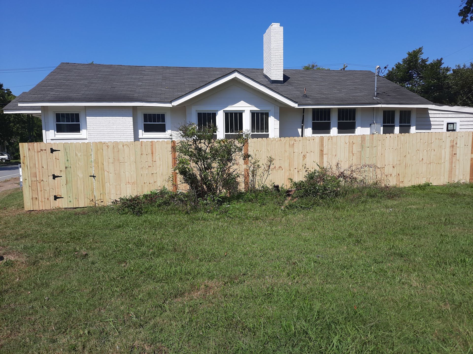 A white house with a wooden fence in front of it.