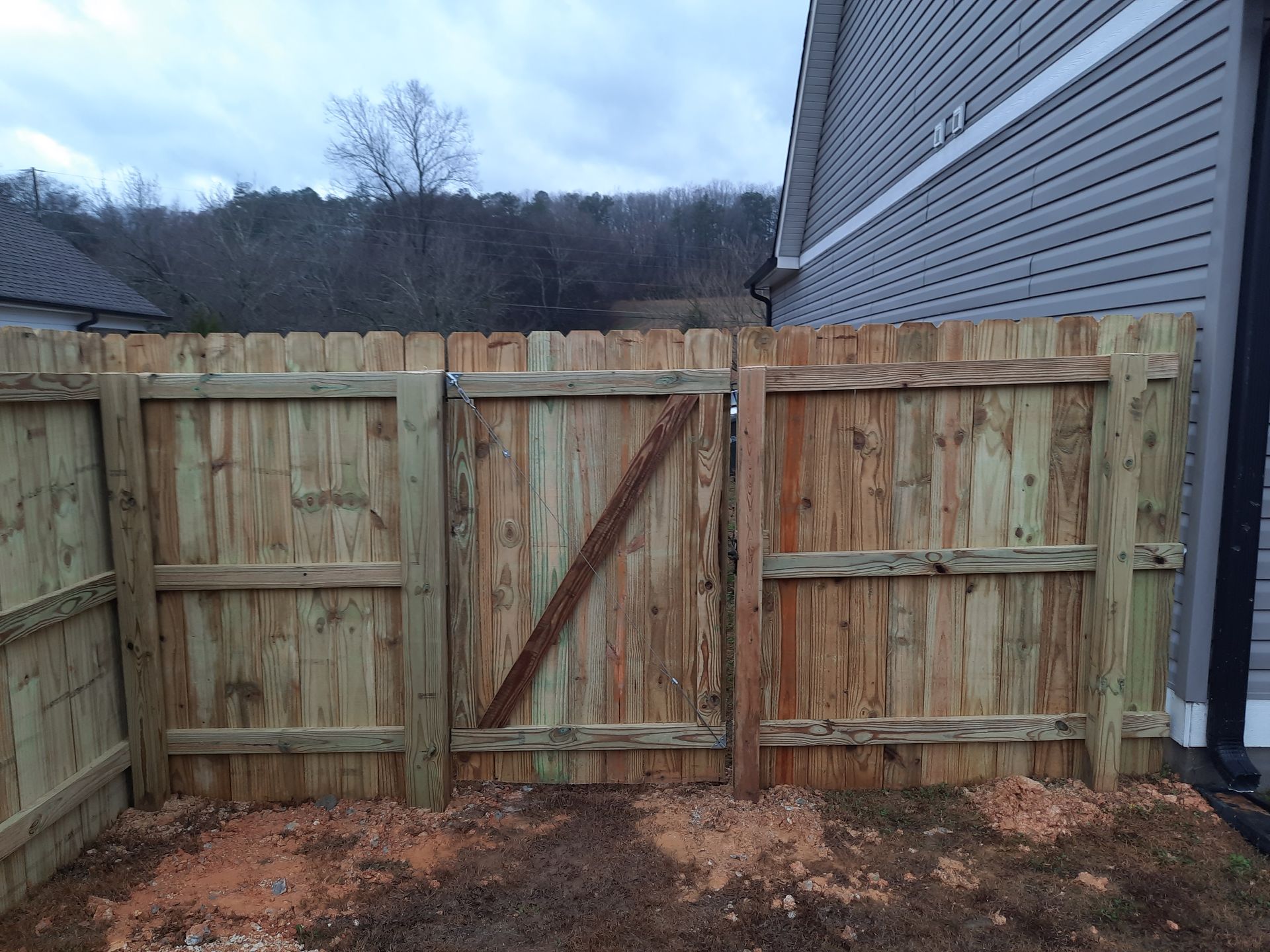 A wooden fence with a gate in the backyard of a house.