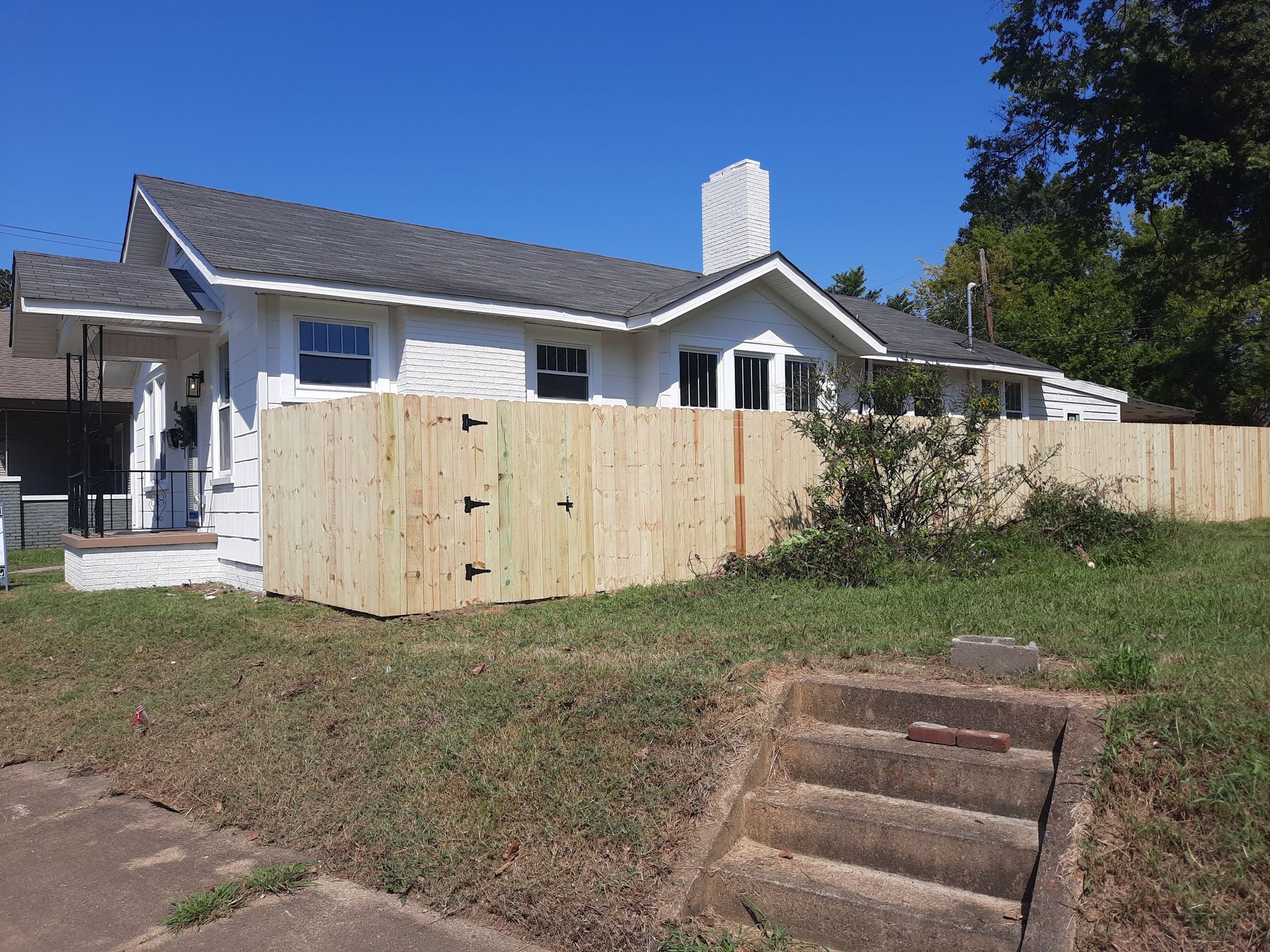 A white house with a wooden fence in front of it.
