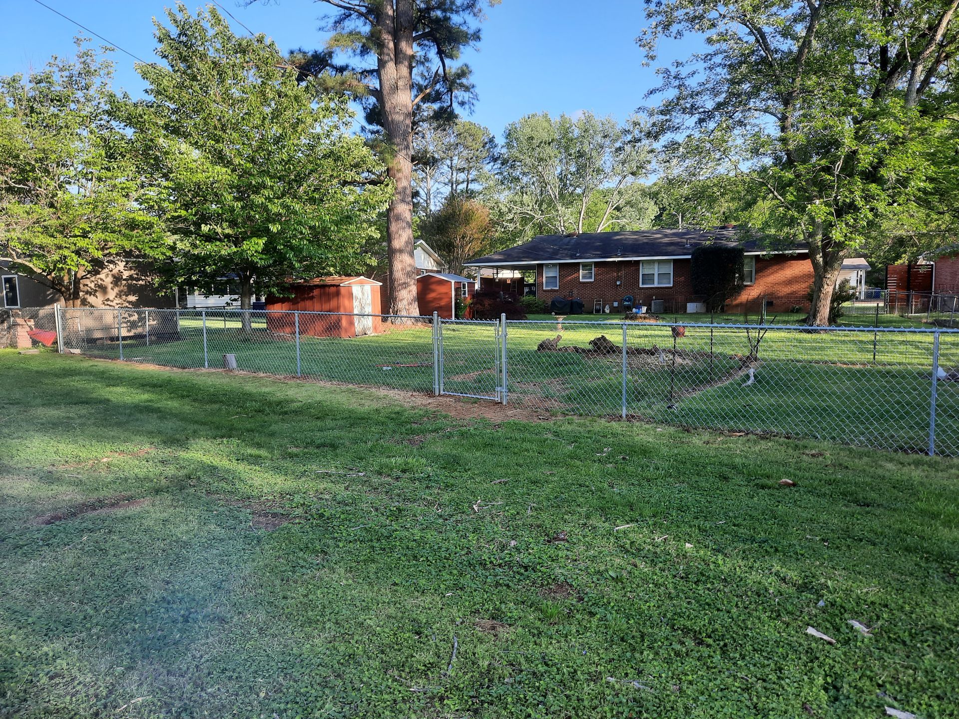 A fenced in yard with a brick house in the background.