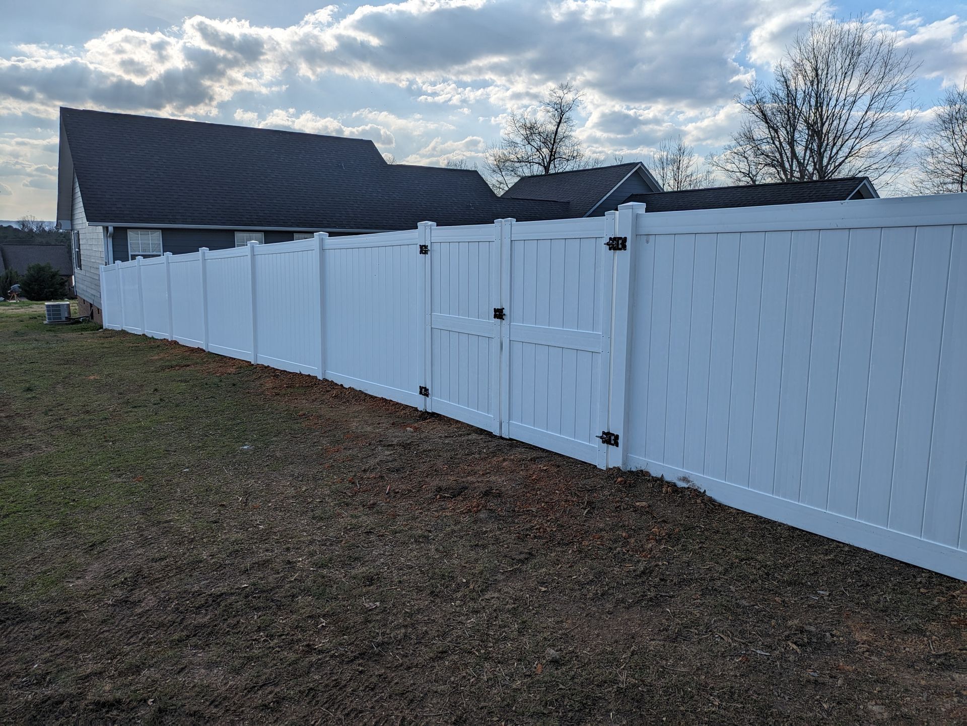 A white vinyl fence with a gate in front of a house.