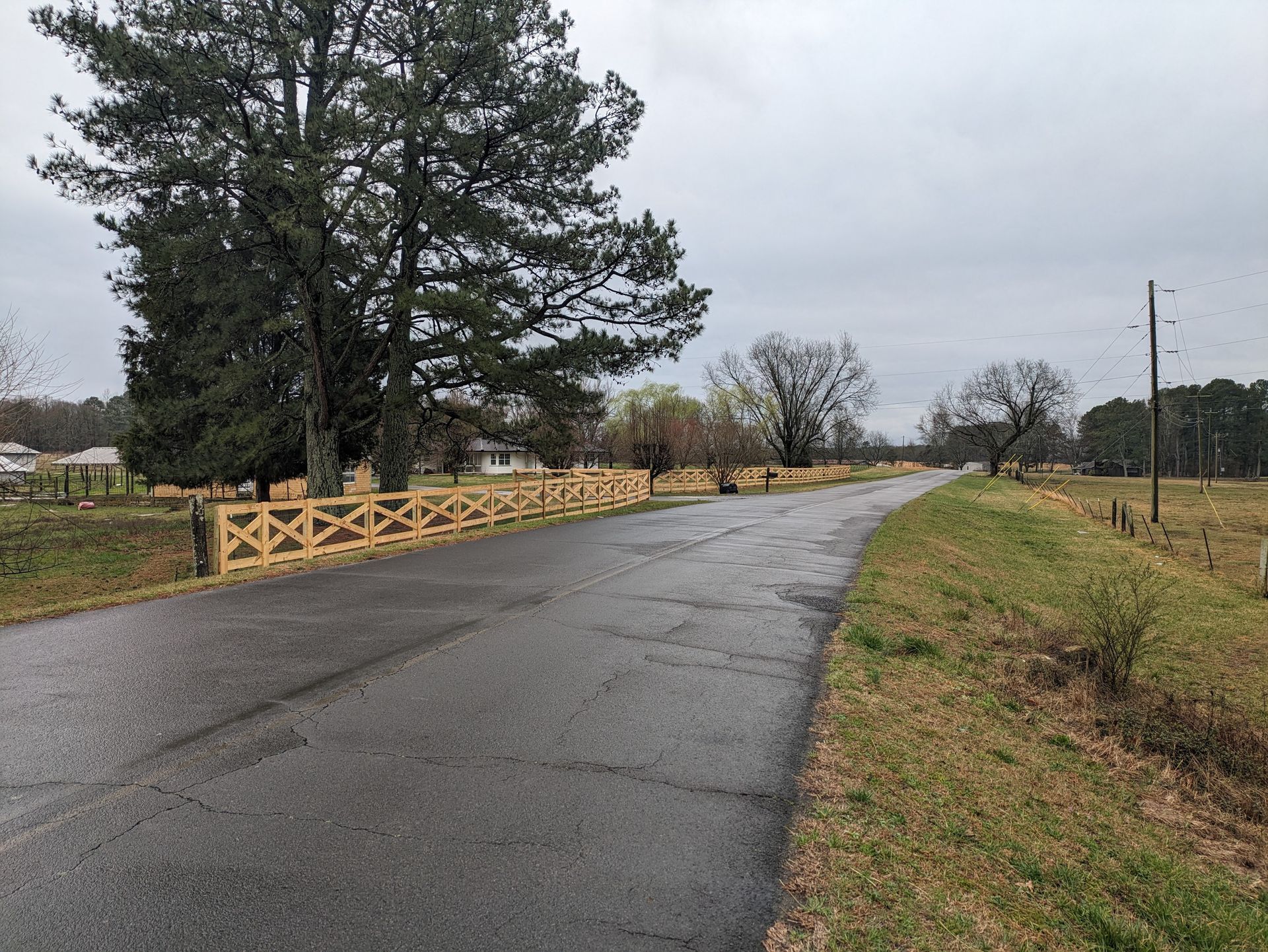 There is a wooden fence along the side of the road.