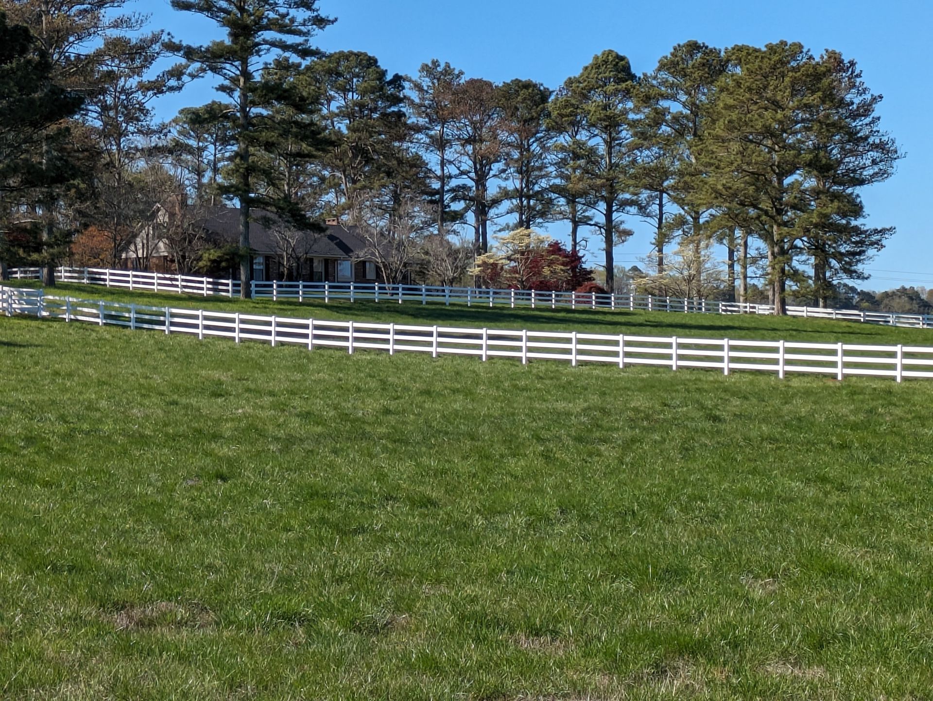A white fence surrounds a stone wall in a yard