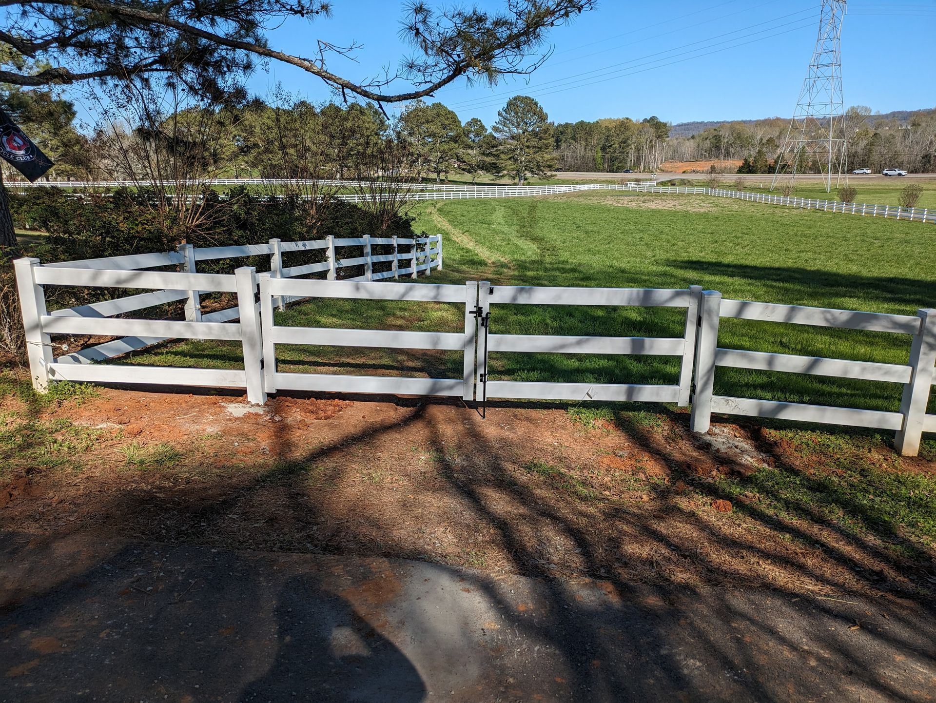 A white fence surrounds a lush green lawn in front of a house.