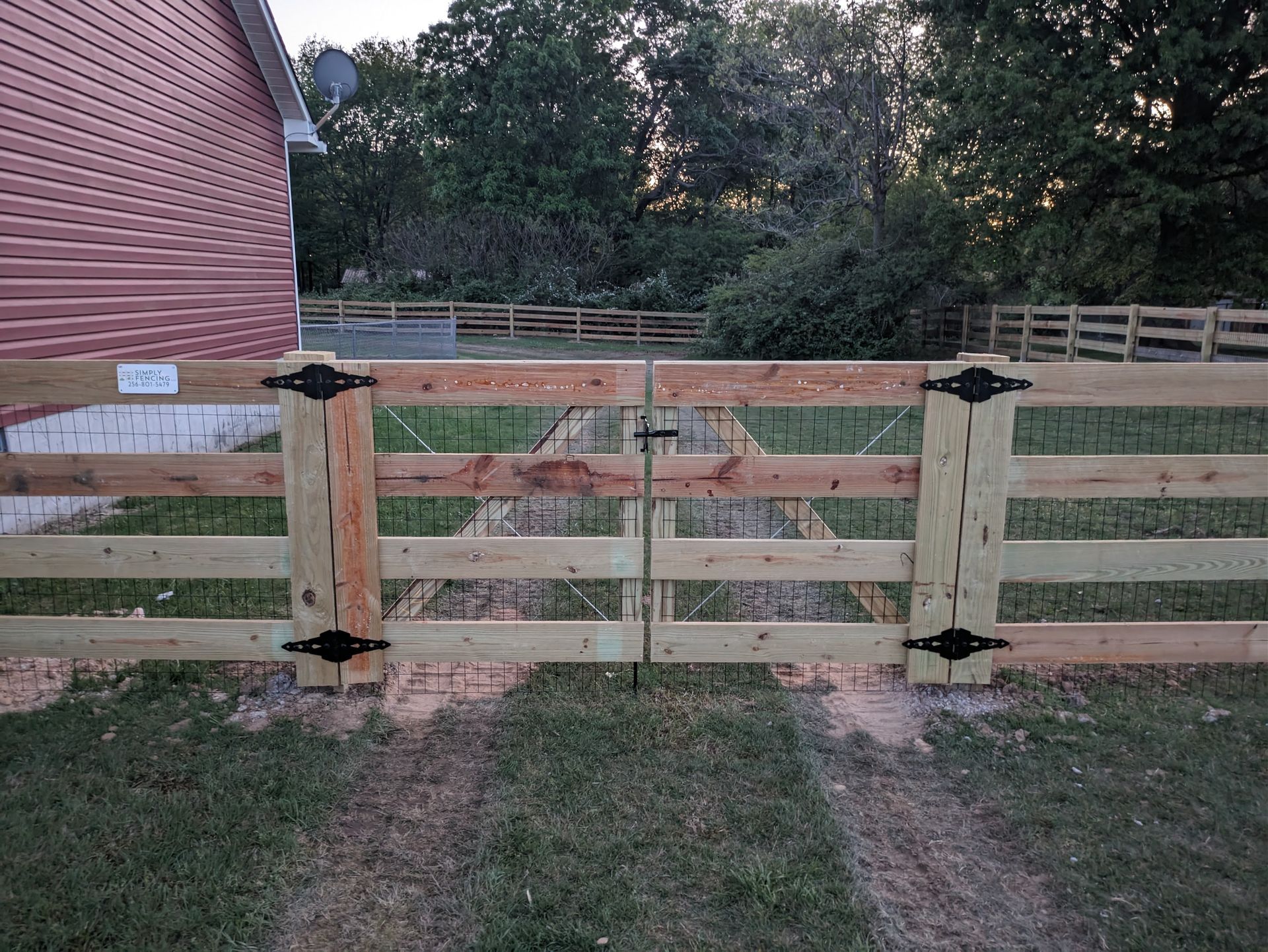 A wooden fence with a gate in front of a house.