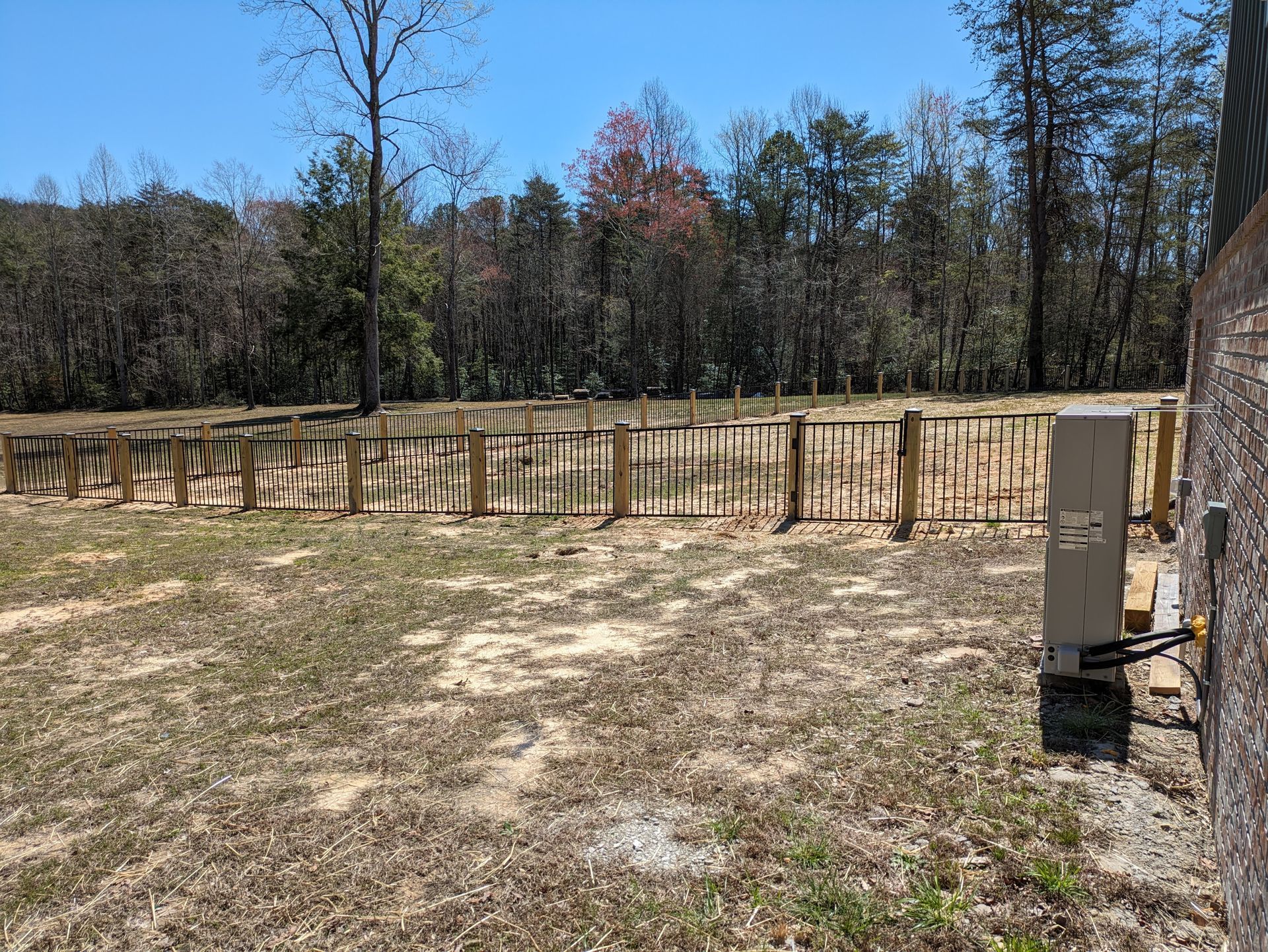 There is a fence in the middle of a field with trees in the background.