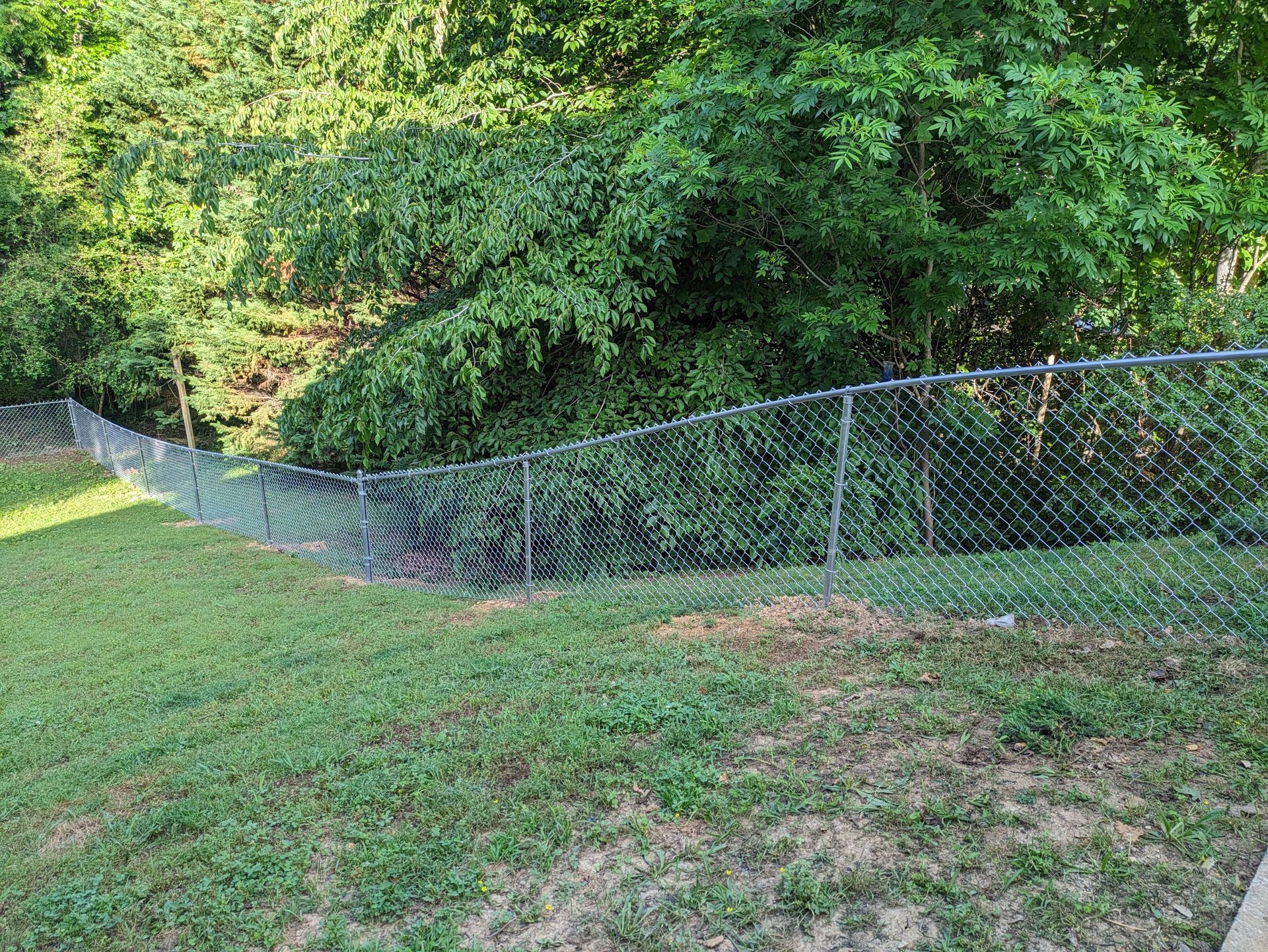 A chain link fence surrounds a lush green field.