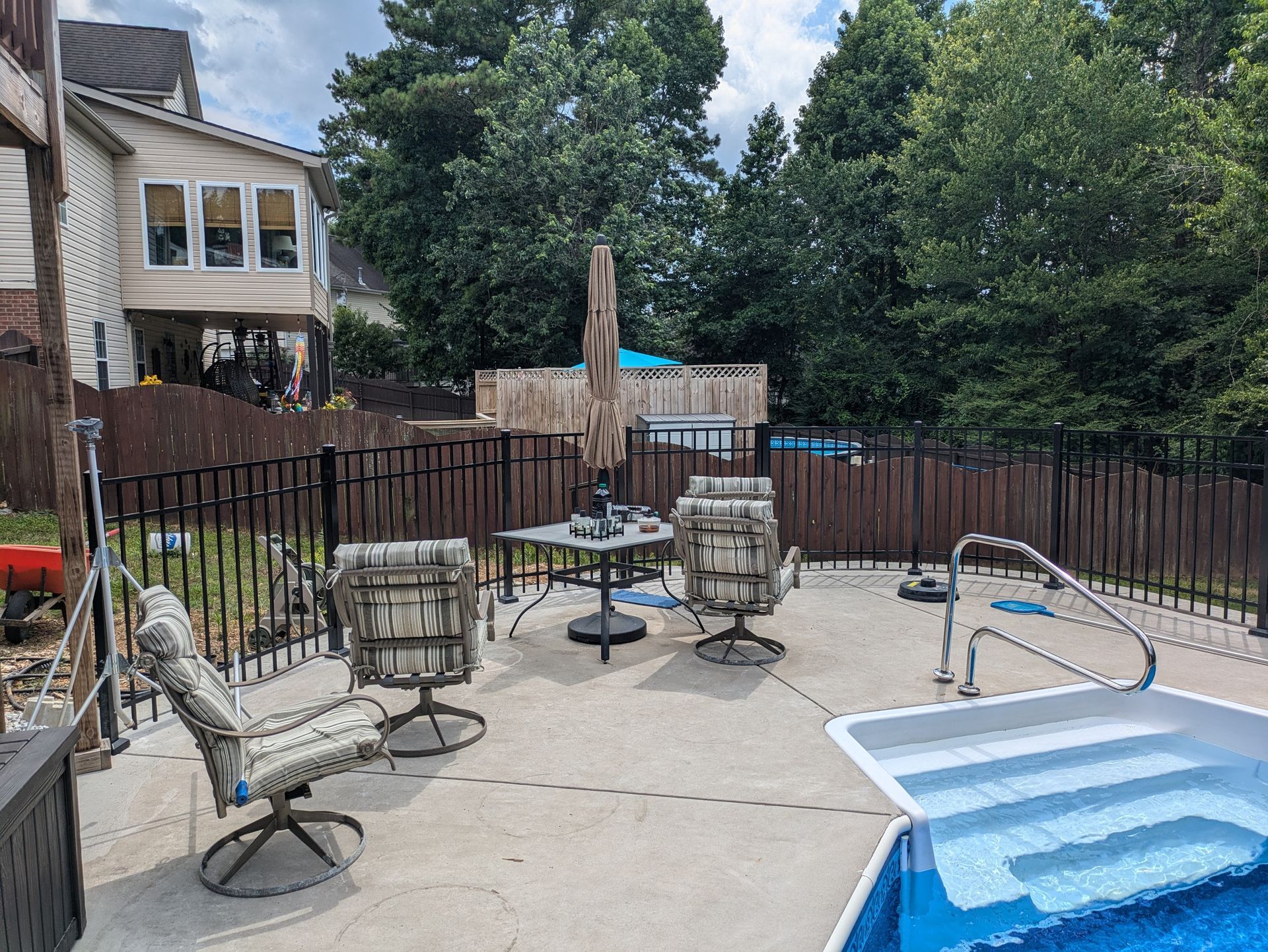 A patio with chairs , tables and umbrellas next to a pool.
