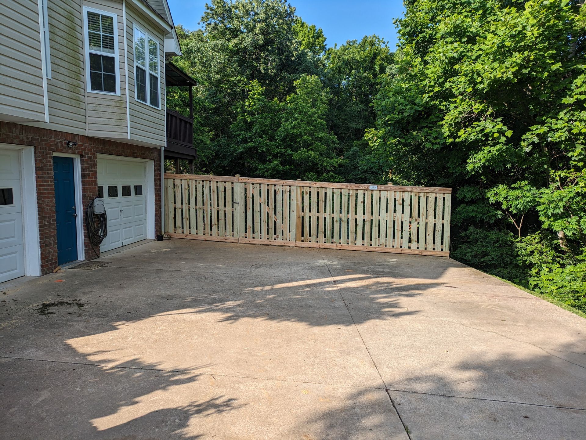 A wooden fence is sitting in a driveway next to a house.