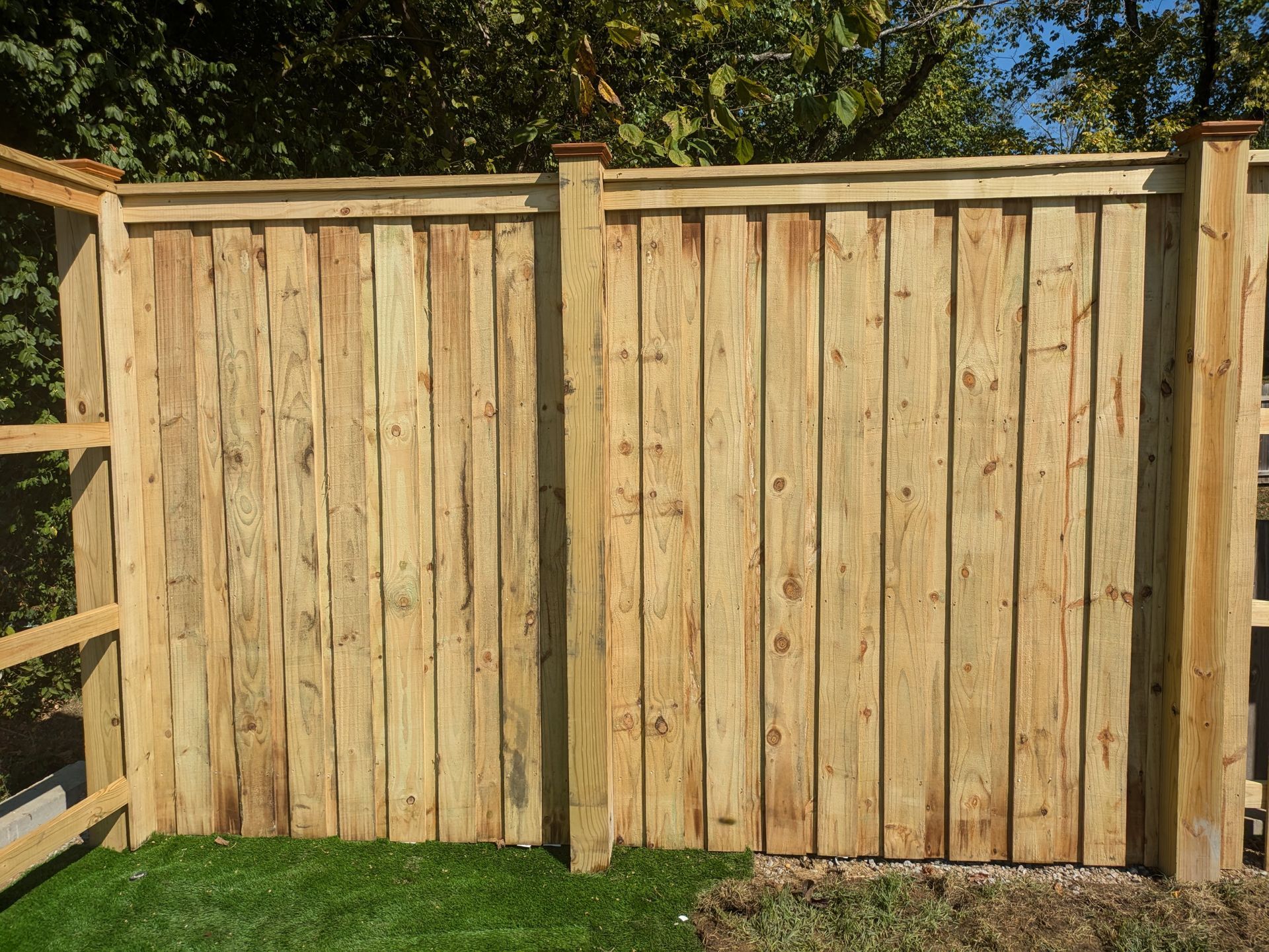 A wooden fence is sitting on top of a lush green field.