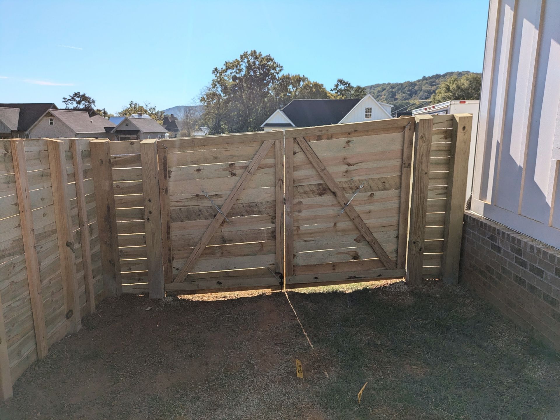 A wooden fence with a gate in the backyard of a house.