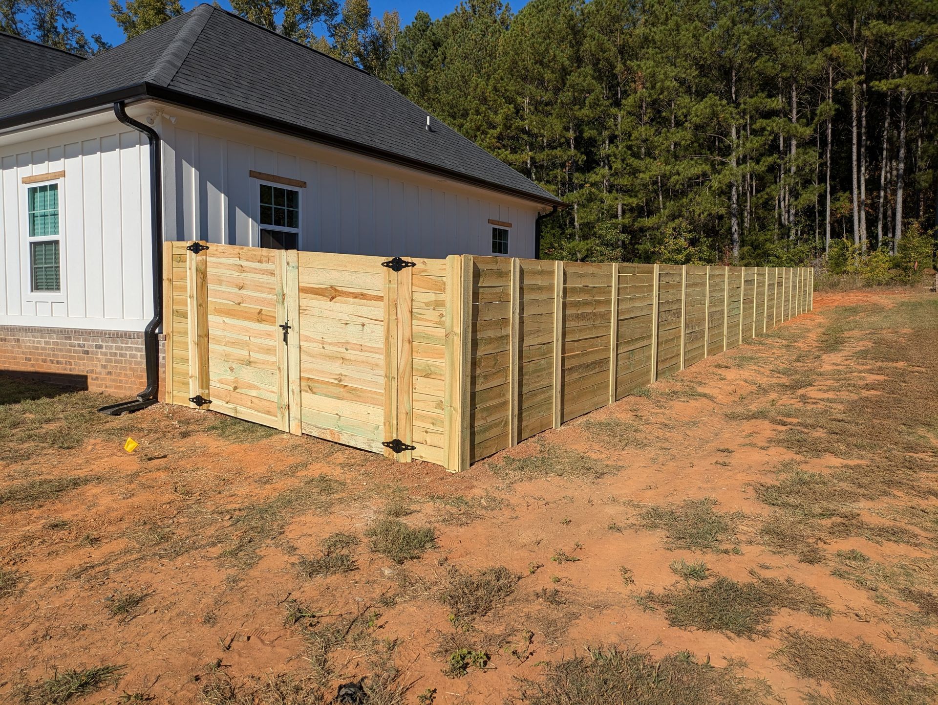 A wooden fence is in the backyard of a house.