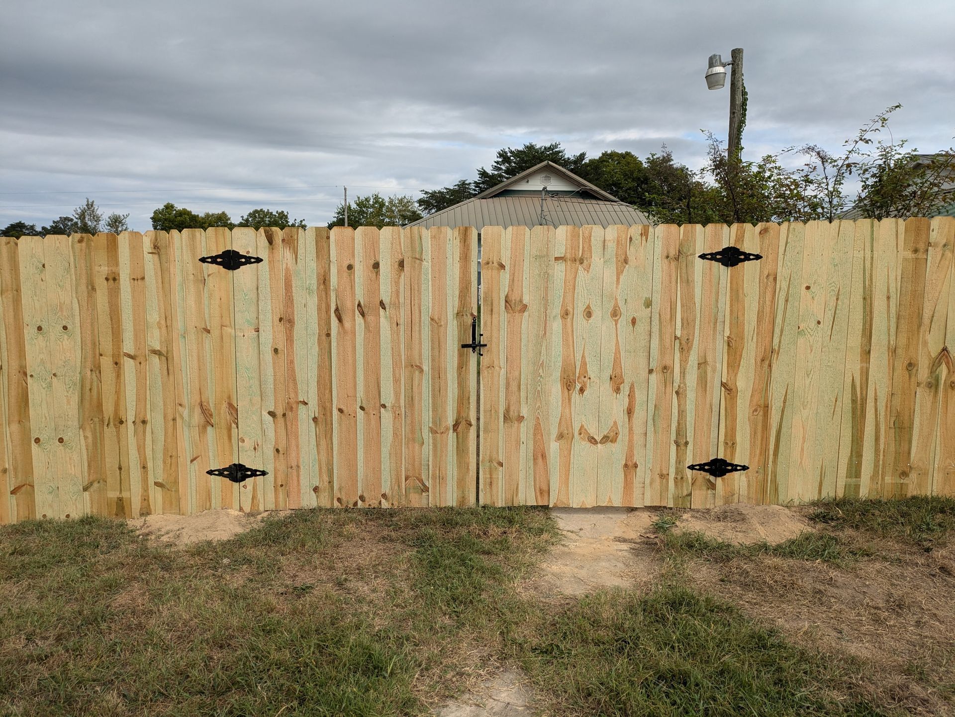 A wooden fence with a gate in the middle of a grassy field.