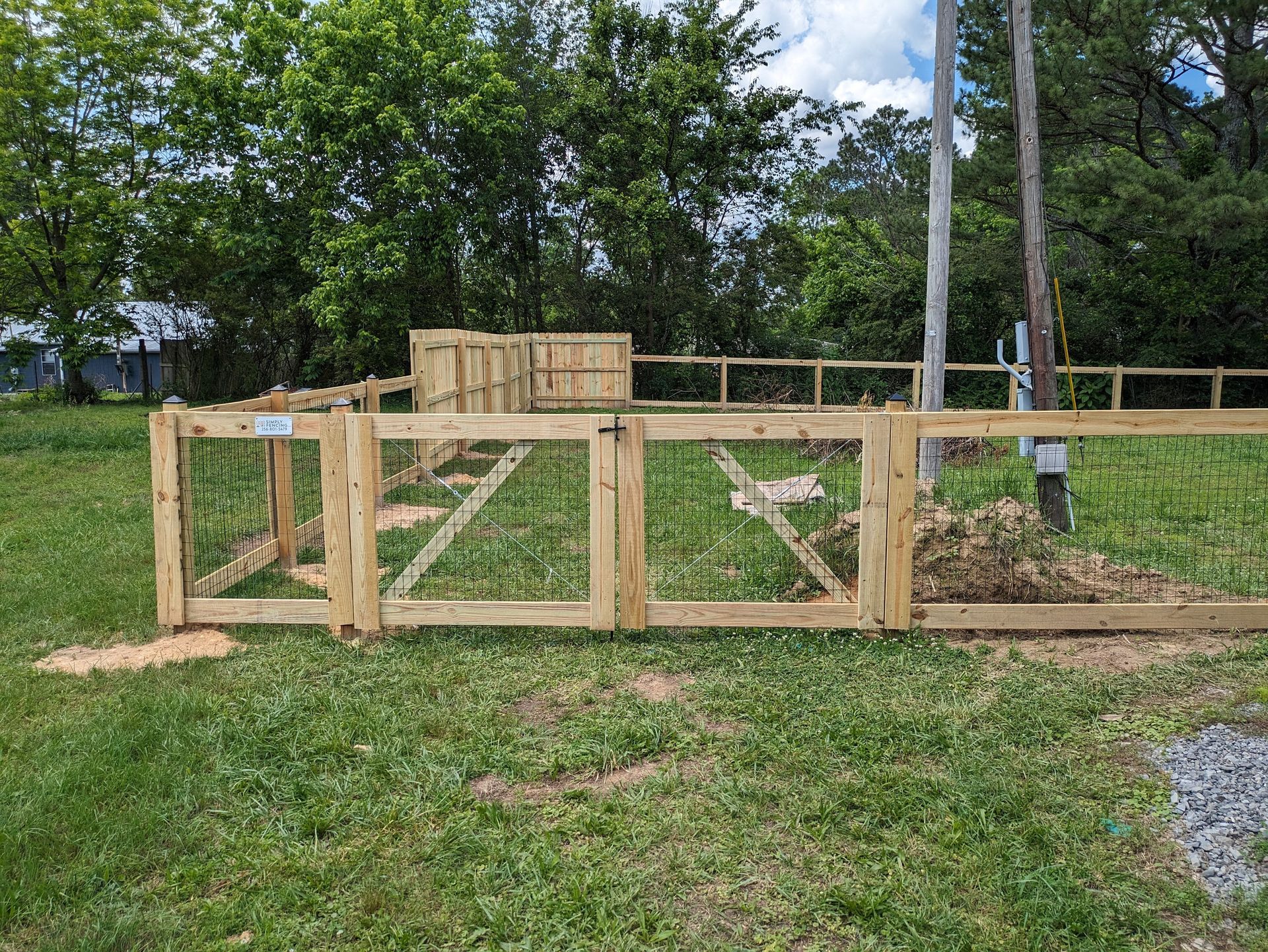 A wooden fence with a gate in the middle of a grassy field.