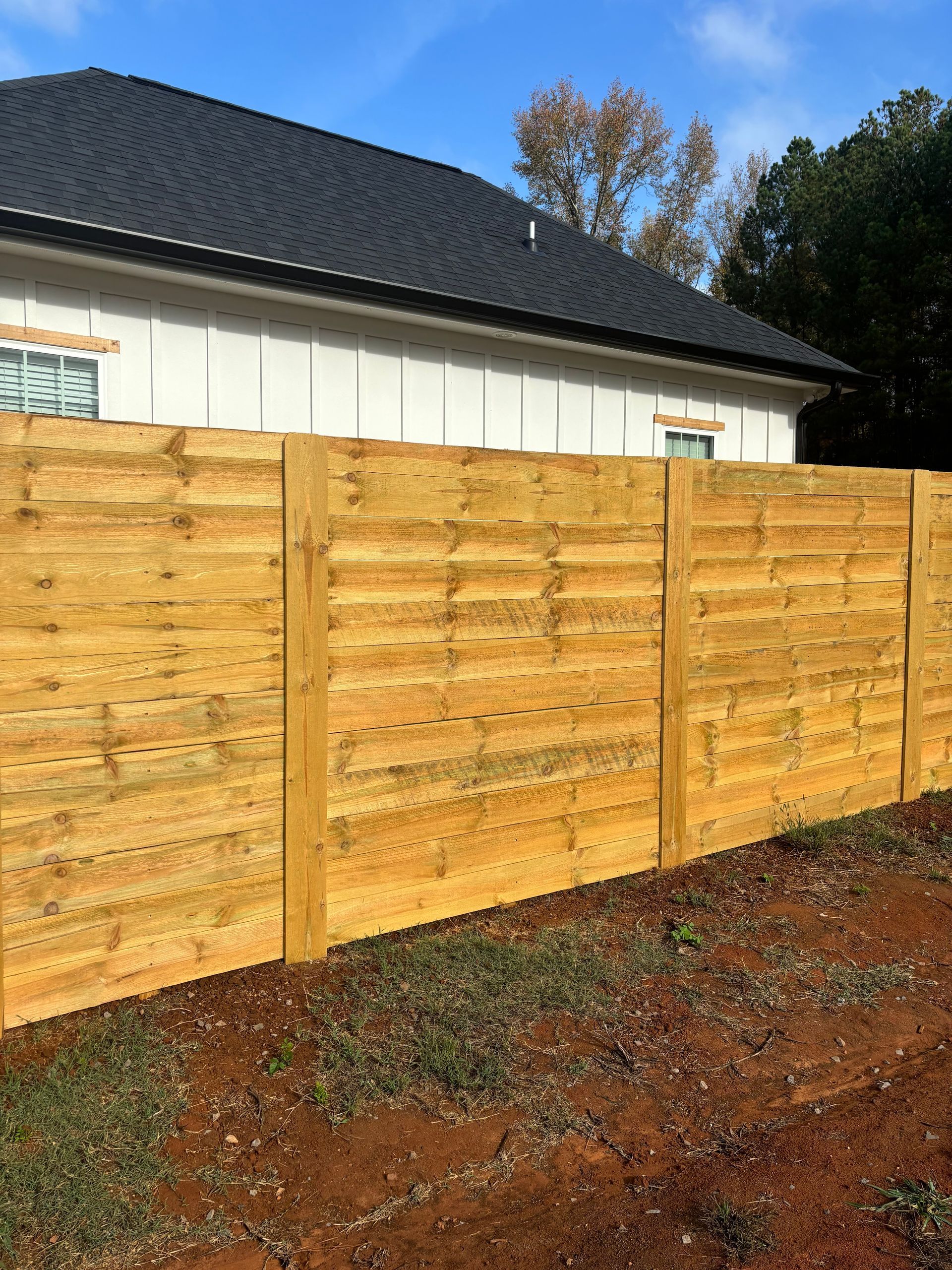 A wooden fence is sitting in front of a house.