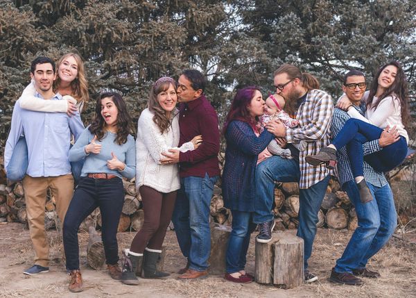 A large family posing for a picture in front of a pile of logs.